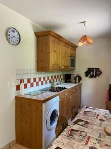 a kitchen with a washing machine and a clock on the wall at Les Frahans in Samoëns