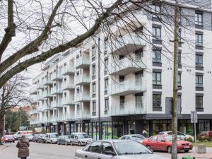 a large white building with cars parked in front of it at VacationClub - Solna Apartment C103 in Kołobrzeg