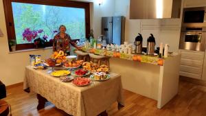 una donna in piedi in una cucina con un tavolo pieno di cibo di Affittacamere Fulé a Fontecchio