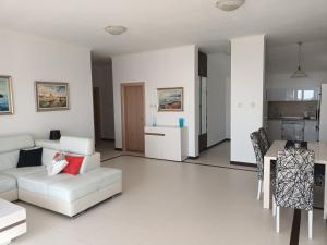 a living room with a white couch and a kitchen at Lustica-Apartment Dora2 in Herceg-Novi
