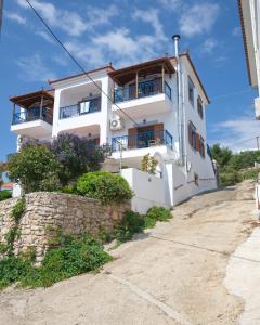 a white house with blue balconies on a hill at Kavos Apartments in Patitiri