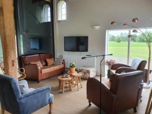 een woonkamer met banken en een flatscreen-tv bij B&B Joostink in Vorden in Vorden