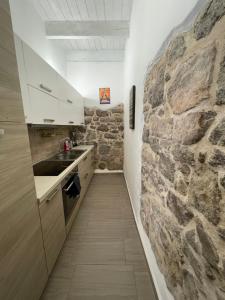 a kitchen with a stone wall and a sink at APPARTAMENTO S.ANTIOCO in SantʼAntìoco