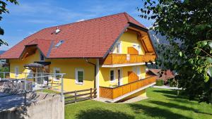 żółto-pomarańczowy dom z czerwonym dachem w obiekcie Appartement Zirkl / Haus Gloria w mieście Haus im Ennstal