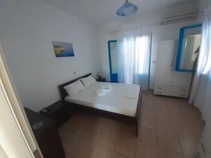 a small bedroom with a white bed and a window at Taxiarchis Studios in Áyios Yeóryios