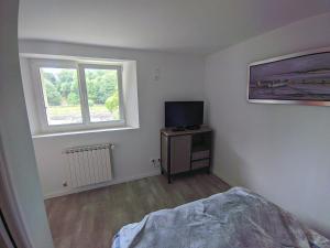 een slaapkamer met een bed, een televisie en een raam bij Appartement entier, vue sur rivière & cathédrale. in Plouguiel