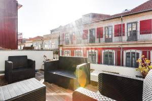 a balcony with chairs and tables on a building at Almada Luxurious Duplex by DA'HOME in Porto