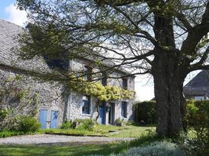 a large stone house with a tree in the yard at Gîte 7ici in Blaimont