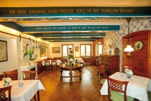 Gästehaus am Herrendeich في نوردستراند: مطعم بطاولات وكراسي و لوحة