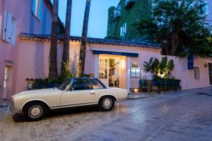a white car parked in front of a building at Hôtel Le Yaca in Saint-Tropez
