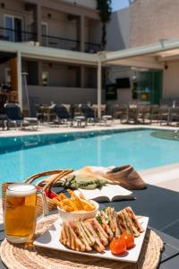 einen Tisch mit einem Teller Essen neben einem Pool in der Unterkunft Telesilla Hotel in Kontokali