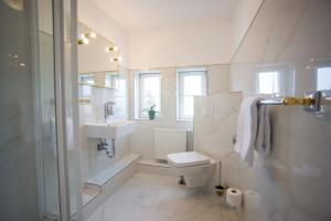 a white bathroom with a toilet and a sink at Gästehaus am Herrendeich in Nordstrand