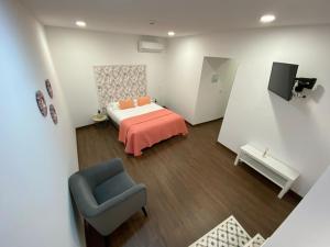 a bedroom with a bed and a blue chair at Concept Guest House in Elvas