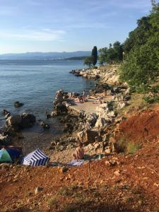 a group of people laying on a beach near the water at Apartman Kora in Njivice