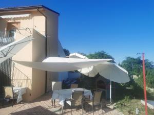 eine Terrasse mit Tischen und weißen Sonnenschirmen neben einem Gebäude in der Unterkunft Casa Valloni in Castiglione Messer Raimondo