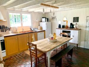 una cocina con mesa de madera y sillas. en La Ferme Familiale, en Faverolles