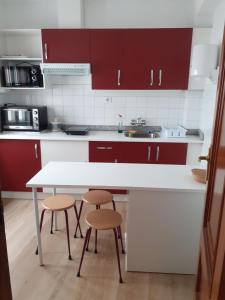 cocina con armarios rojos, mesa blanca y taburetes en Pensión Río Umia, en Caldas de Reis