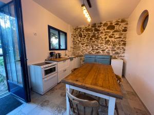 een keuken met een houten tafel en een stenen muur bij Les 3 pigeons in Bressuire