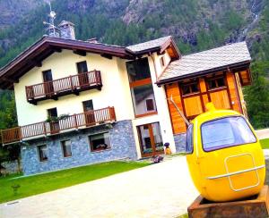 une voiture jaune garée devant une maison dans l'établissement Fohre1748, à Gressoney-La-Trinité