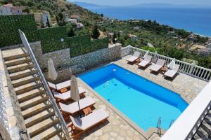 a swimming pool with chairs and a villa at Sunset villas in Qeparo