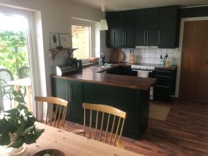 une cuisine avec des armoires noires et un comptoir en bois dans l'établissement Gatehouse at unique farm, neighbour to yaks & emus, à Höör