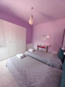 two beds in a room with purple walls and a table at Affittacamere Appartamento colorato in Ferrara