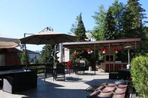 un patio con mesas, sillas y una sombrilla en Casa Anne Marie, en Sinaia