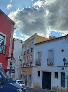 a group of buildings on a street with a cloudy sky at Concept Guest House in Elvas