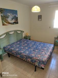 Schlafzimmer mit einem Bett mit blauer Decke in der Unterkunft Les jardins d'armand in Valras-Plage
