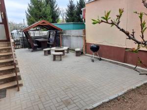 une terrasse avec un barbecue, une table de pique-nique et des bancs dans l'établissement Faragó Apartman, à Nyíregyháza