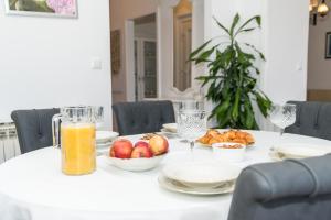 una mesa blanca con fruta y un vaso de zumo de naranja. en Apartments Doris, en Zadar