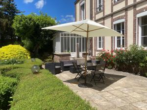 a patio with a table and an umbrella at L'Avre des Joncherets - proche center parc les Bois Francs in Saint-Lubin-des-Joncherets