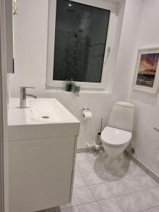 baño con aseo y lavabo y ventana en Løkken centrum ferielejlighed-apartment 4E en Løkken