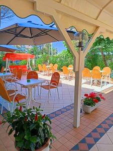 a patio with tables and chairs and an umbrella at Costa del Sole Only Room in Milano Marittima