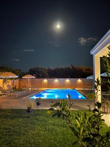 una piscina notturna con la luna nel cielo di Villa Pergola a Pandokrátor