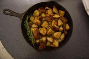a pan filled with fried potatoes with a garnishment at Ray's Bucktown Bed and Breakfast in Chicago