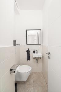 a white bathroom with a toilet and a sink at Apartment near Volksoper - Modern, Big, Central, Cosy in Vienna