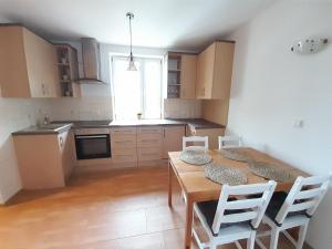 a kitchen with a wooden table and white chairs at Apartament Koninki in Koninki