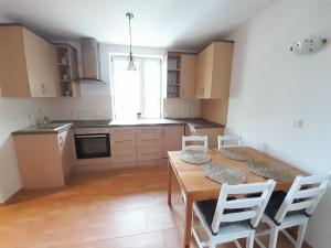 cocina con mesa de madera y sillas blancas en Apartament Koninki en Koninki