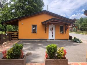 una pequeña casa amarilla con una puerta blanca en Apartmán Lomňanka, en Dolní Lomná