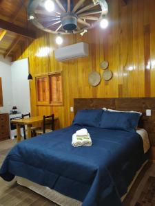 a bedroom with a blue bed with two towels on it at Aconchego da Serra Geminados in São Joaquim