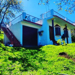 Casa situada en una colina con césped y balcón en Kodai sakthi guest house, en Kodaikanal