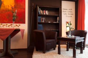 a living room with a table and two chairs and a book shelf at Hotel Heide Residenz in Paderborn