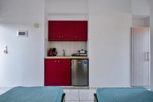 een keuken met rode kasten en een roestvrijstalen koelkast bij Villa Maria Apts in Kato Gouves