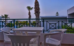 een tafel en stoelen op een balkon met uitzicht op de oceaan bij Villa Maria Apts in Kato Gouves