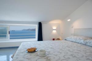 een slaapkamer met een bed met een bord croissants en een raam bij La Mansarda in Praiano