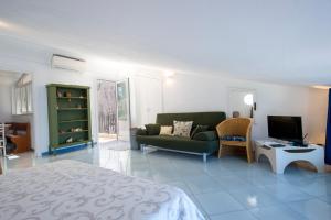 een woonkamer met een groene bank en een televisie bij La Mansarda in Praiano