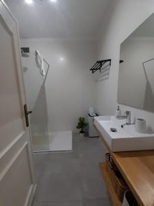 ein weißes Badezimmer mit einem Waschbecken und einem Spiegel in der Unterkunft Amália Rodrigues -apartamento com 3 quartos em pleno coração de Ílhavo in Ílhavo