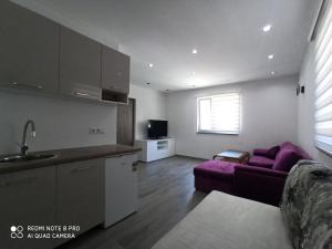 een keuken en een woonkamer met een paarse bank bij Apartmani Kula in Tuzla
