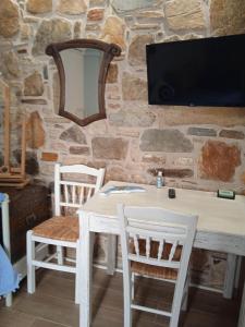 a table with two chairs and a tv on a stone wall at Artistic house in Kokkari